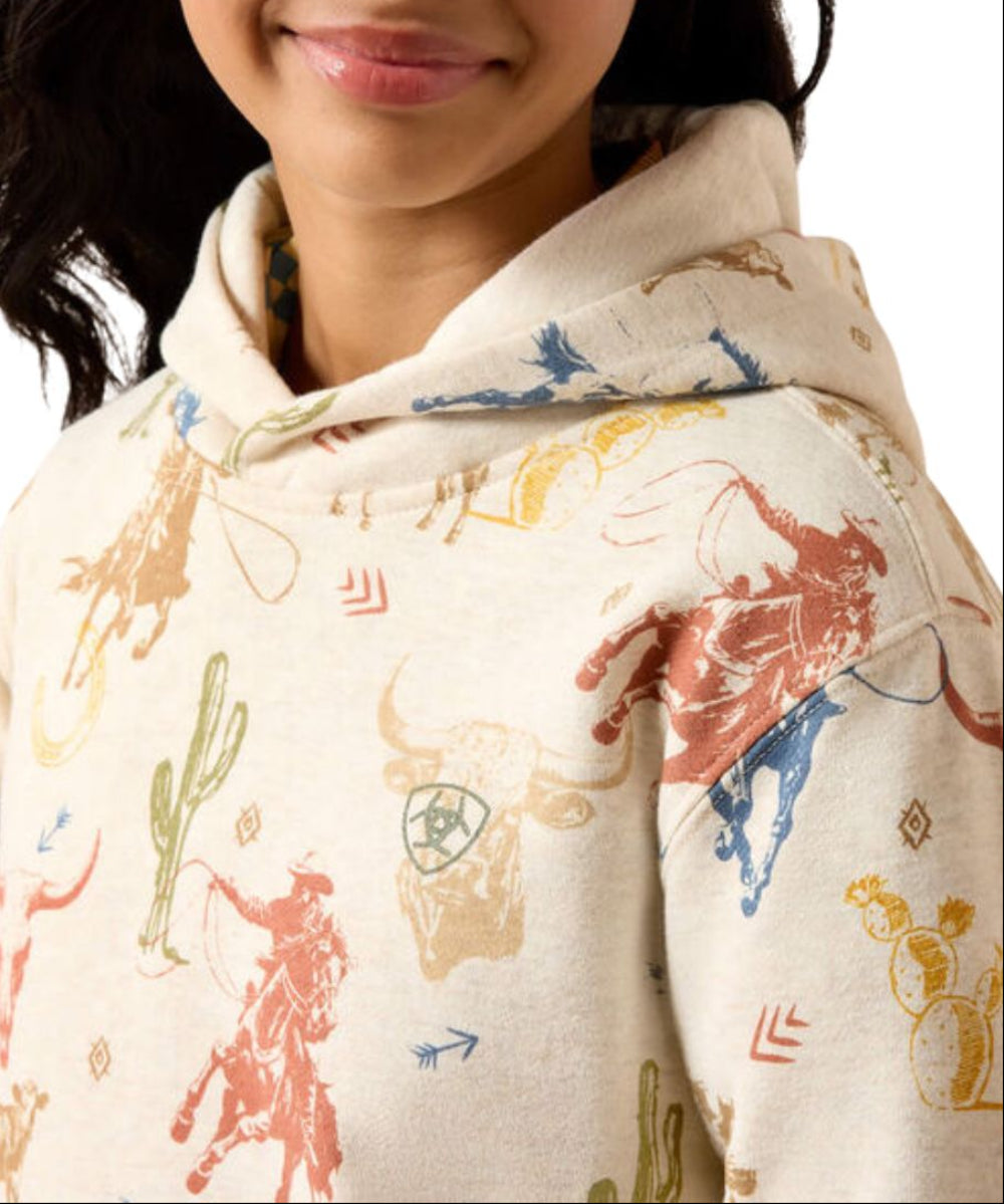 Close-up view of the girl's cream-colored hooded sweatshirt with a colorful western-themed print of cowboy boots, cacti, and rodeo animals