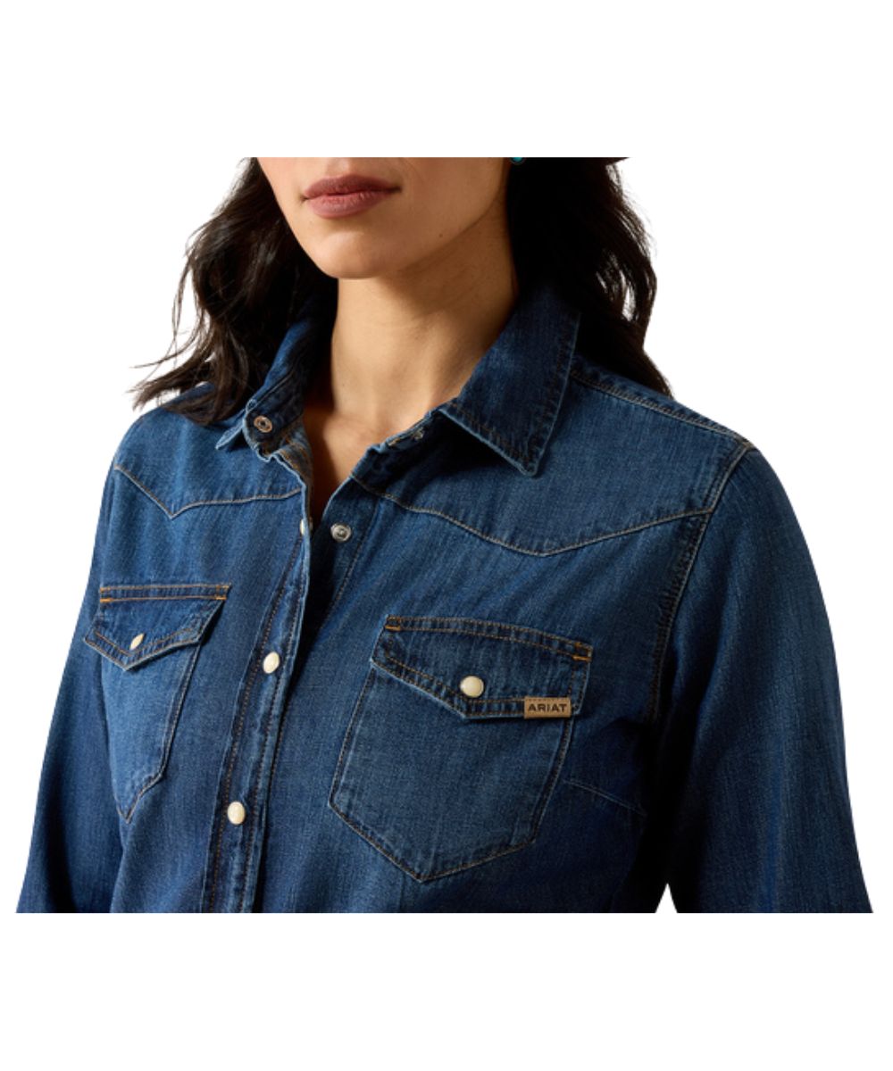 Close-up view of the medium wash denim pearl snap shirt featuring the spread collar and snap flap chest pockets