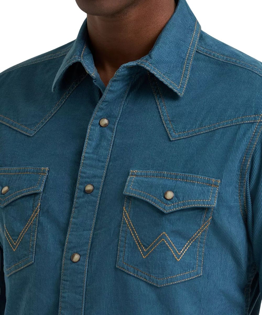 A close-up of a blue cordurory western shirt worn by a model, showing the chest area with two buttoned flap pockets and contrast stitching.