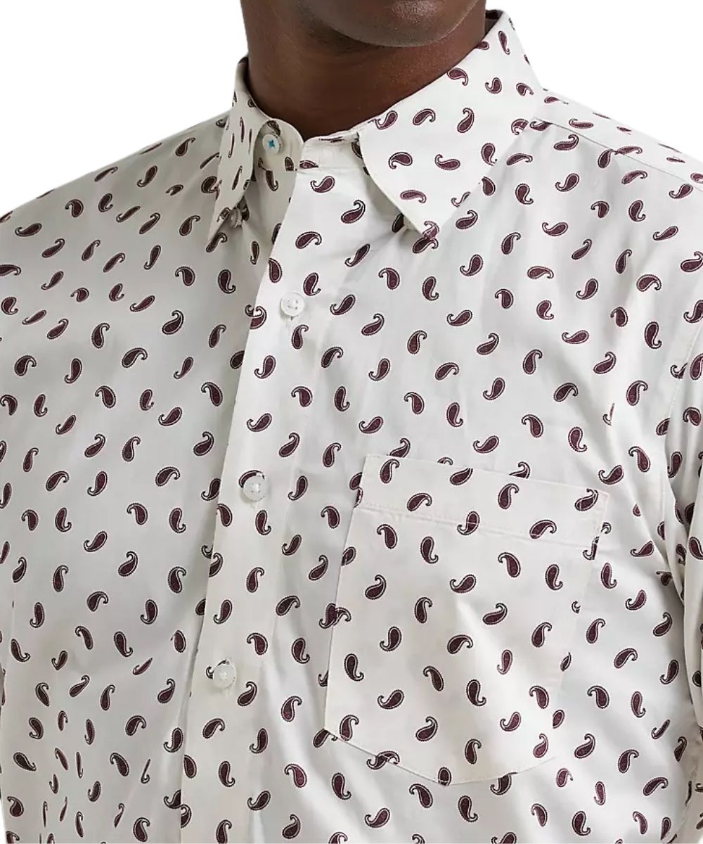 Close-up of a men's button-down shirt with a white base and an all-over dark brown paisley pattern, worn by a model.