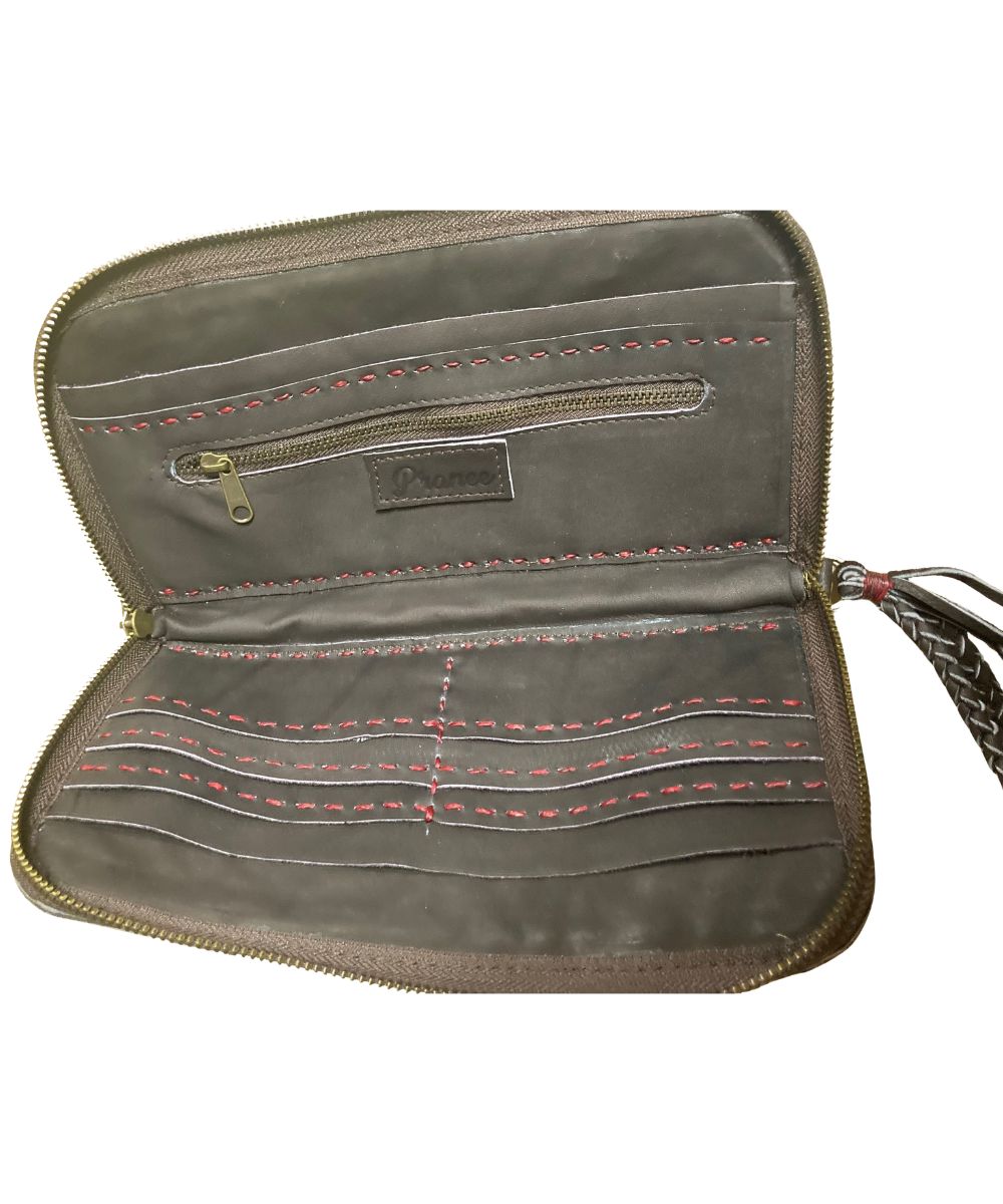 An open zip-around wristlet wallet in brown leather, showing multiple interior card slots, a zip pocket, red contrast stitching, and a braided strap