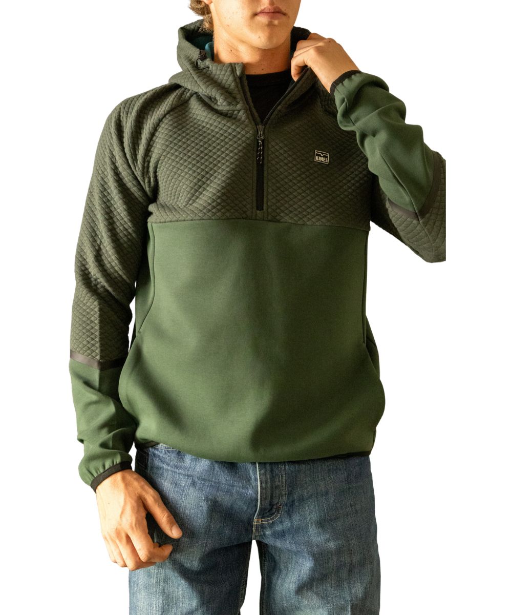 Front view of the men's forest green Kimes Ranch long sleeve pullover featuring the hooded collar with an elastic shock cord, quilted upper body, silicone logo patch at the left chest, side seam welt hand pockets, taped cuffs, and a square hem