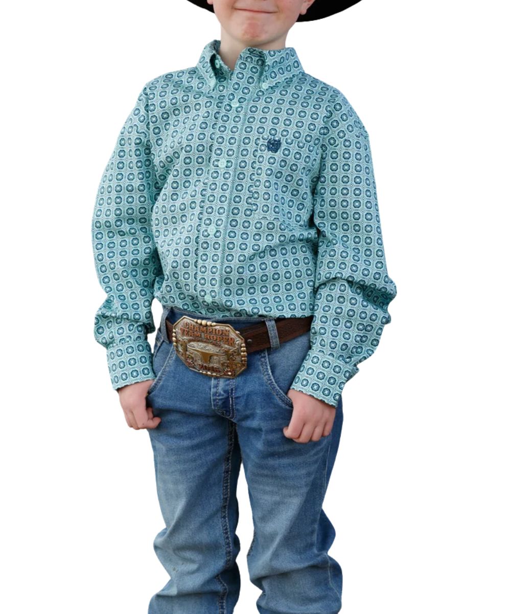 Front view of the boy's turquoise Cinch long sleeve button down shirt featuring the button down collar, turquoise buttons, chest pocket, and geometric print