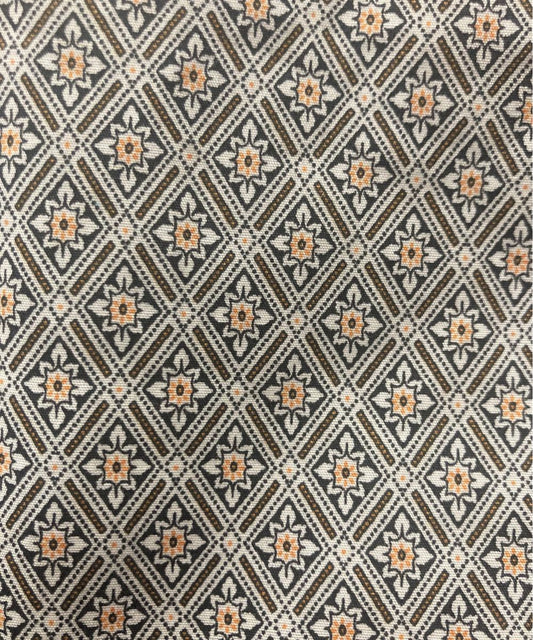 A close-up of a woven fabric with a repeating geometric diamond pattern in brown, beige, and muted orange.