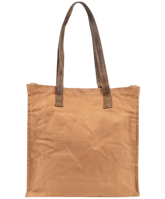 Back view of the tan small tote bag featuring the solid tan canvas back and the brown leather carrying straps