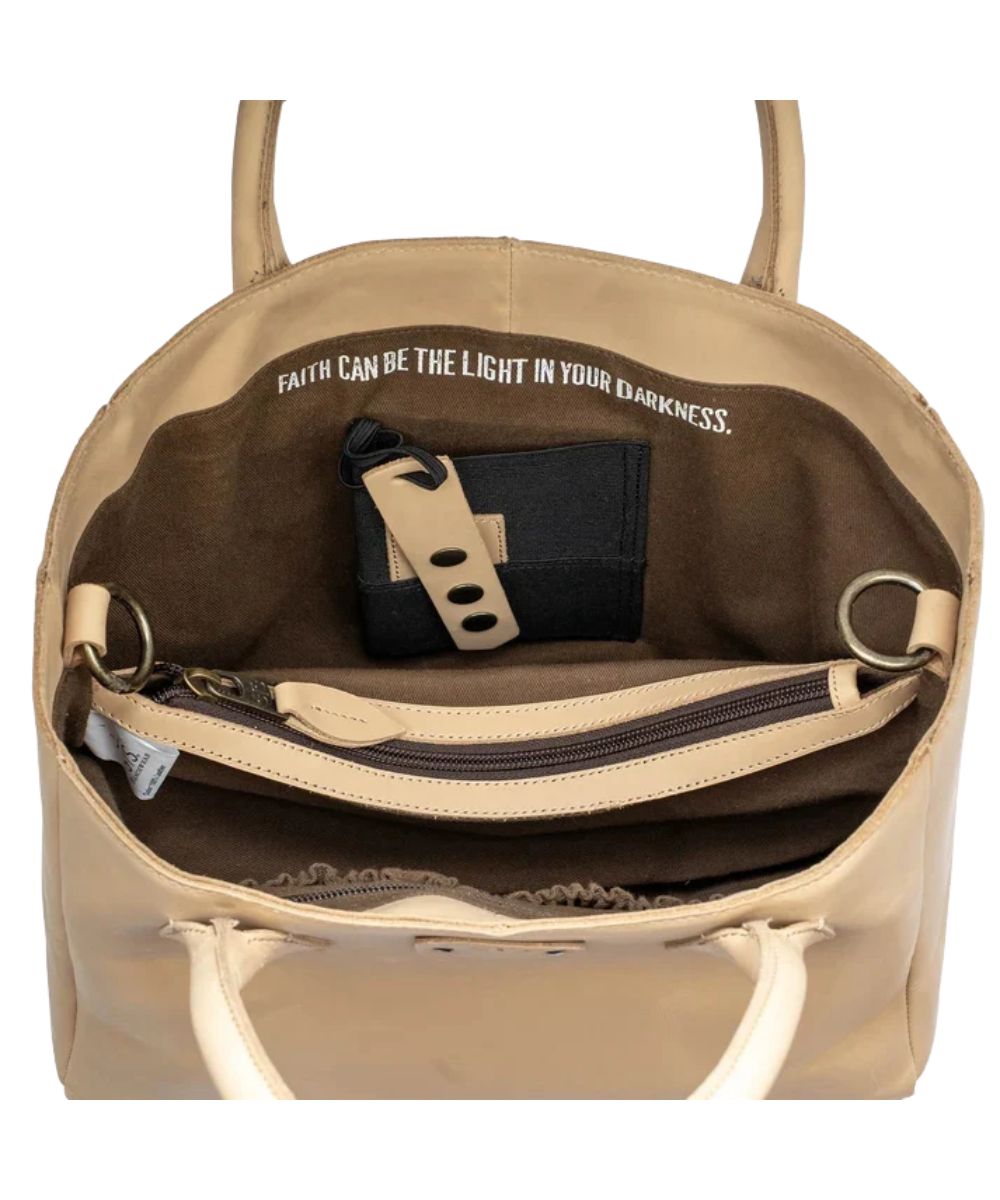 Interior view of the women's beige leather satchel featuring the interior concealed carry pocket and a quote inside that reads: "Faith Can Be The Light In Your Darkness."