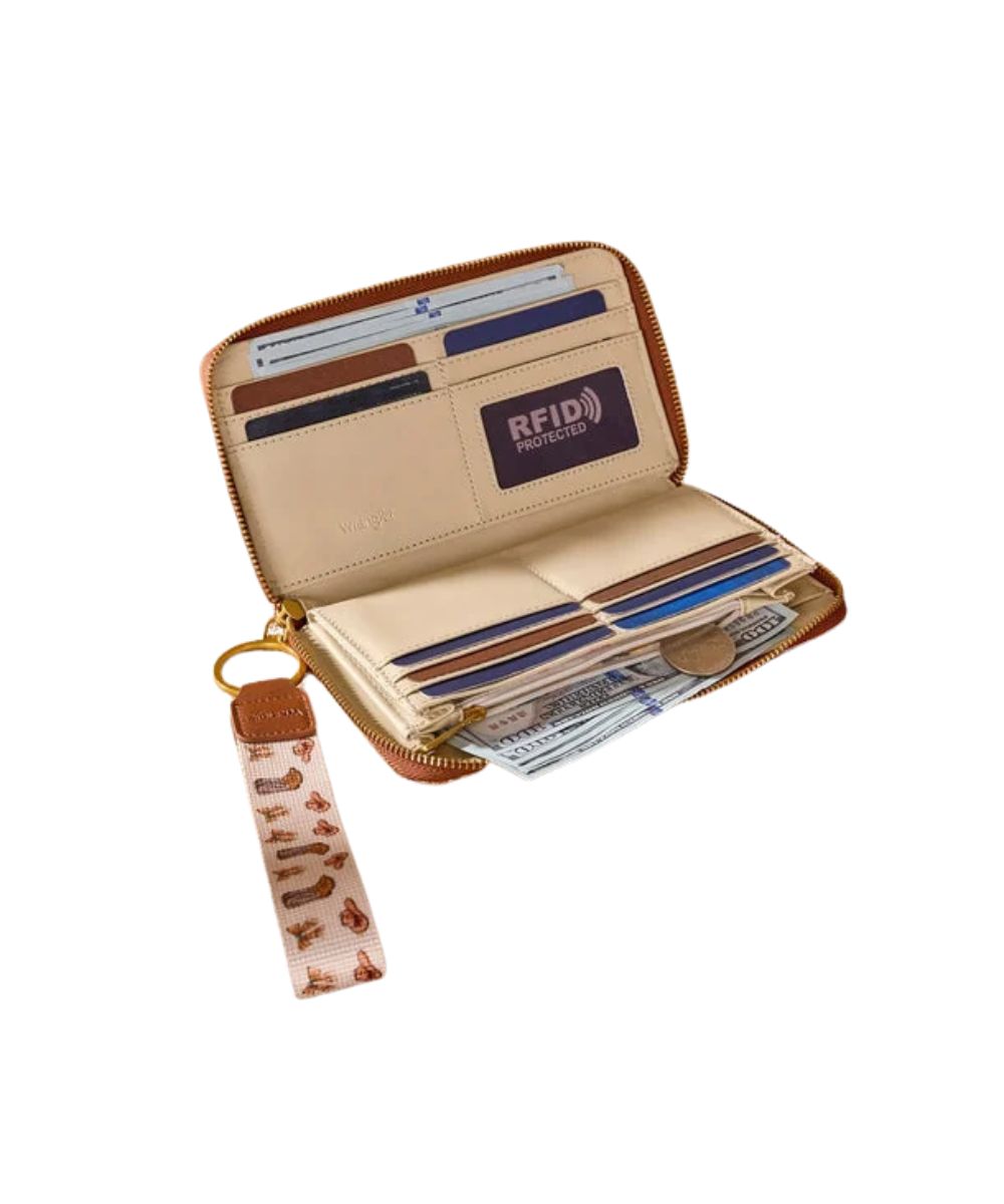 A tan and beige zip-around wallet shown open, with card slots, elastic loops, and a patterned wristlet strap hanging from a gold-tone ring.