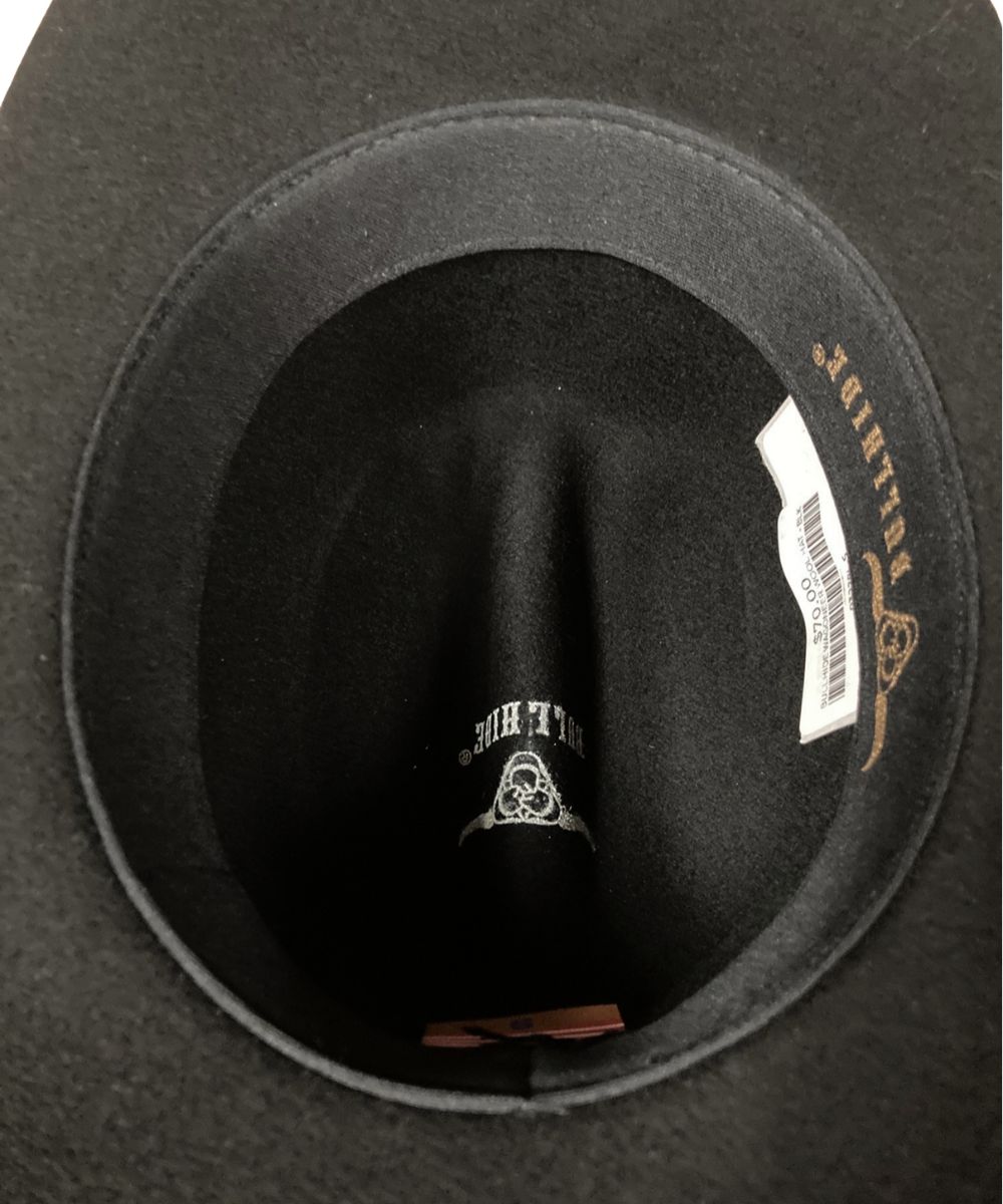 Close-up of the inside of a black felt hat, showing the crown lining, a white product tag, and gold embroidered text reading 'BULLHIDE' on the inner band.