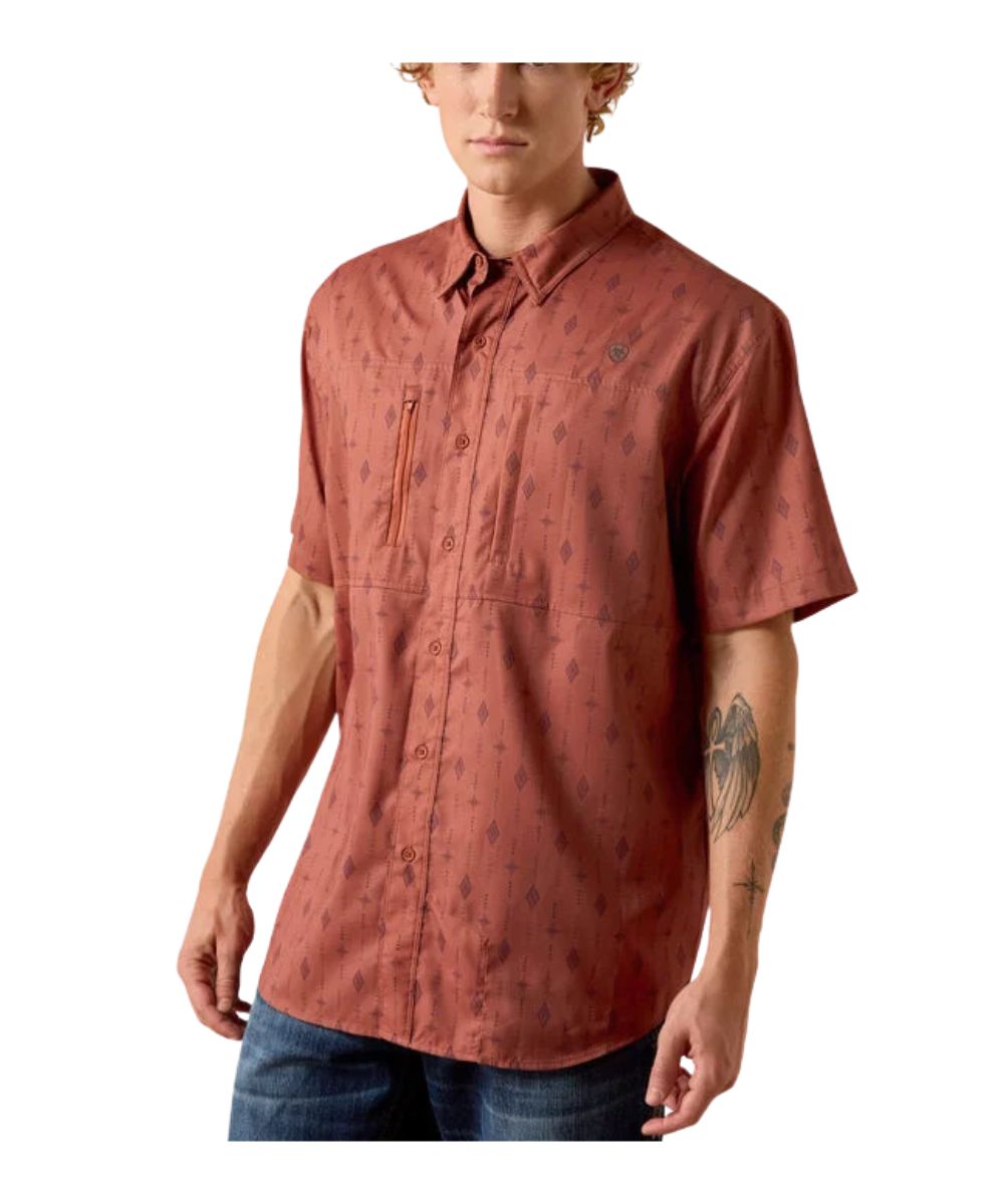 A man wearing a short-sleeve button-up shirt in a rust-orange color with a subtle dark geometric pattern, paired with blue jeans, shown against a plain white background.