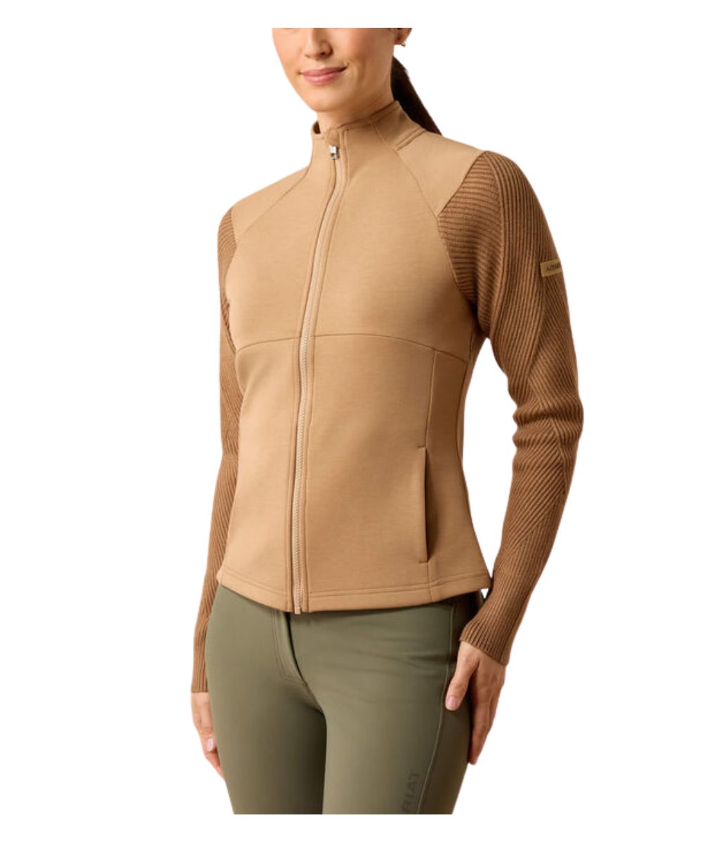 A woman wearing a tan and brown zip-up athletic jacket with textured knit sleeves, paired with olive green leggings, shown against a plain white background.