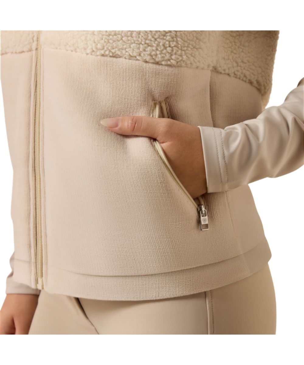 Close-up view of the cream sherpa fabric and zippered hand pockets