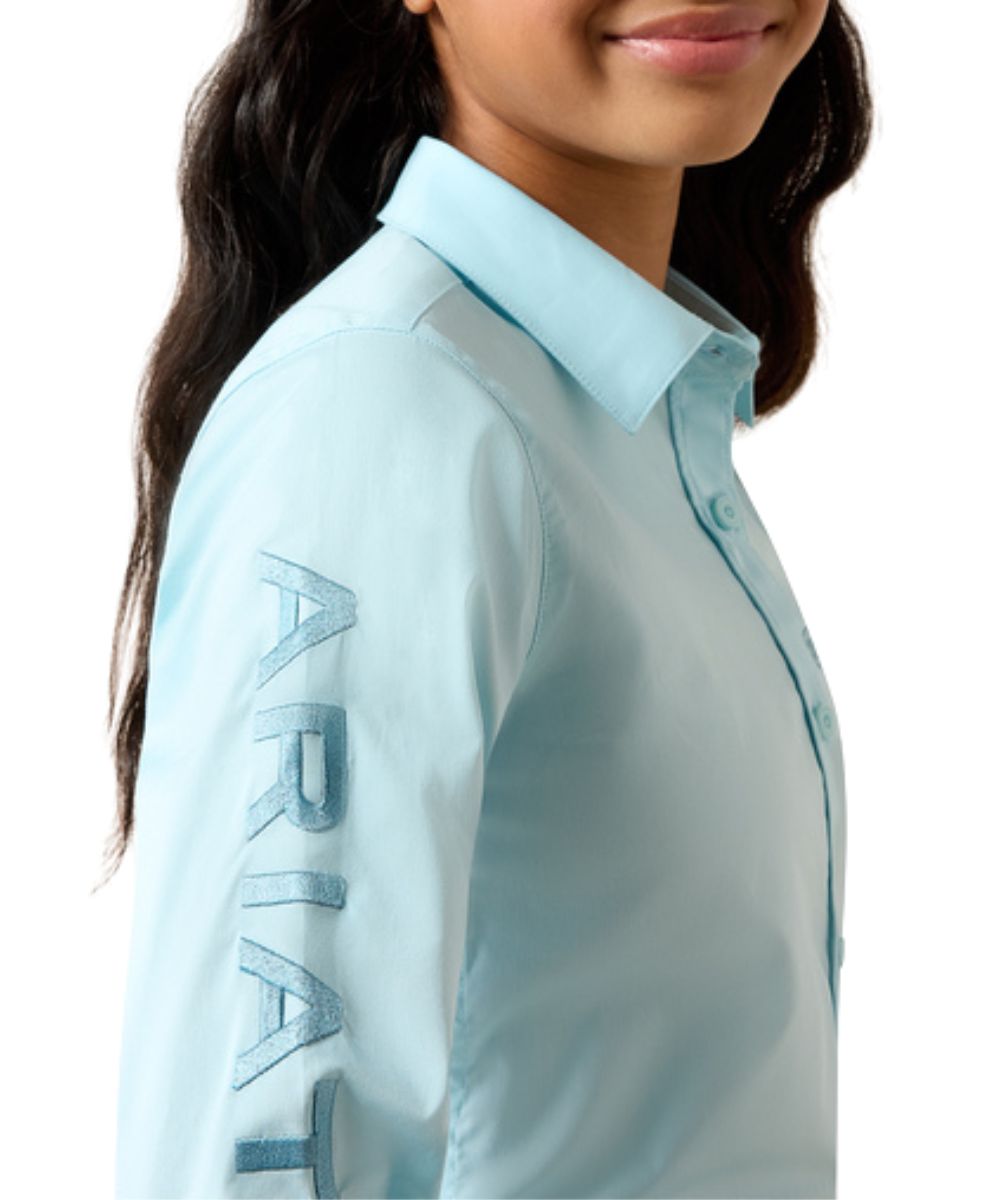 Close-up view of the girl's solid saltwater henna long sleeve button down shirt featuring the logo embroidery down the right sleeve