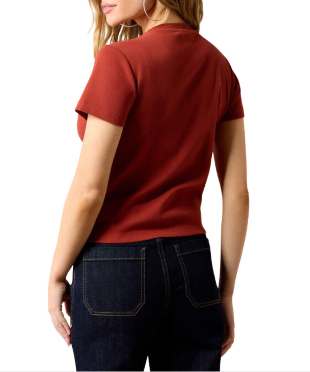 A woman shown from the back wearing a rust-red short-sleeve crewneck t-shirt and dark blue jeans, set against a plain white background.