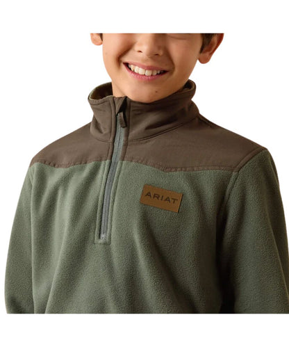 A child wearing an olive green and brown quarter-zip fleece pullover with a brown 'ARIAT' logo patch on the chest, shown against a plain white background.