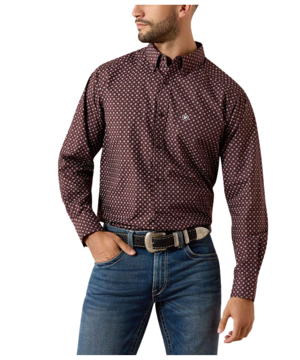 A man wearing a long-sleeve button-down shirt with a small white geometric pattern on a dark burgundy base, paired with blue jeans and a black belt, shown against a plain white background.