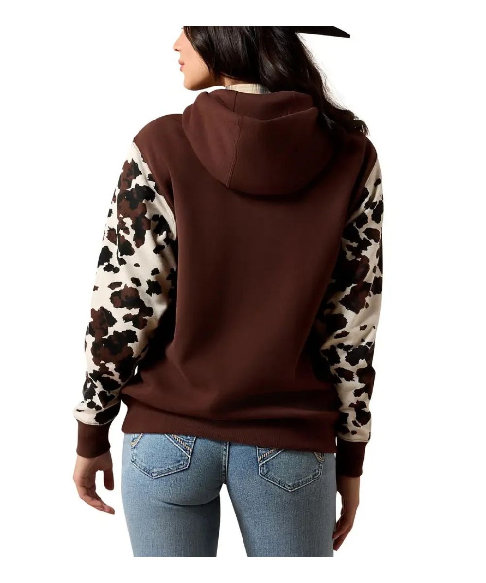 A woman shown from the back wearing a brown hooded sweatshirt with leopard-print sleeves, paired with light blue jeans, against a plain white background.