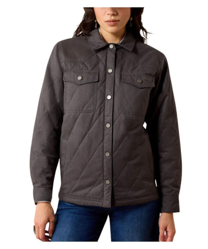 A woman wearing a dark gray quilted button-up jacket with chest flap pockets, paired with blue jeans, shown against a plain white background.