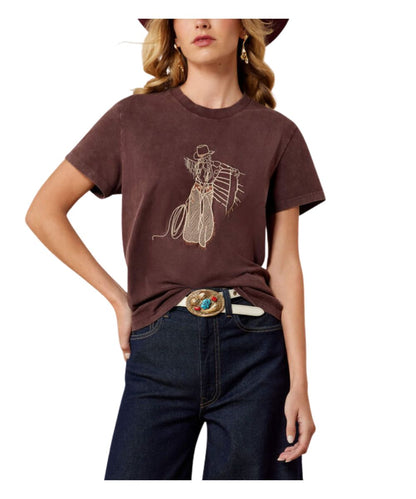 A woman wearing a brown short-sleeve graphic t-shirt with a western-style outline illustration, paired with dark blue jeans and a western belt, against a plain white background.