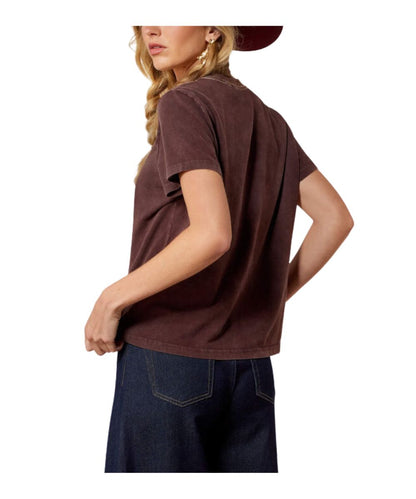 A woman wearing a dark brown short-sleeve t-shirt and dark blue jeans, shown from a side-back angle against a plain white background.