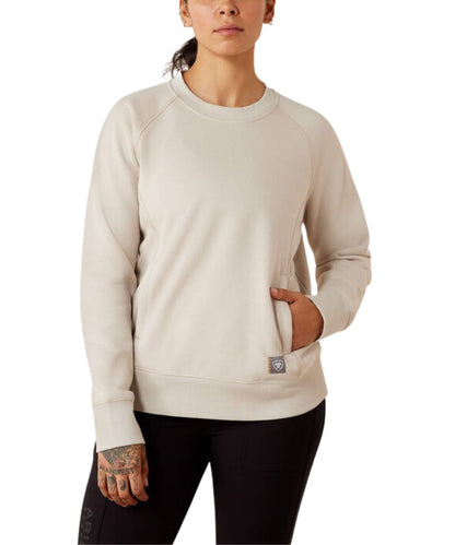 A woman wearing a light beige crewneck sweatshirt with a kangaroo pocket, paired with black leggings, shown against a plain white background.