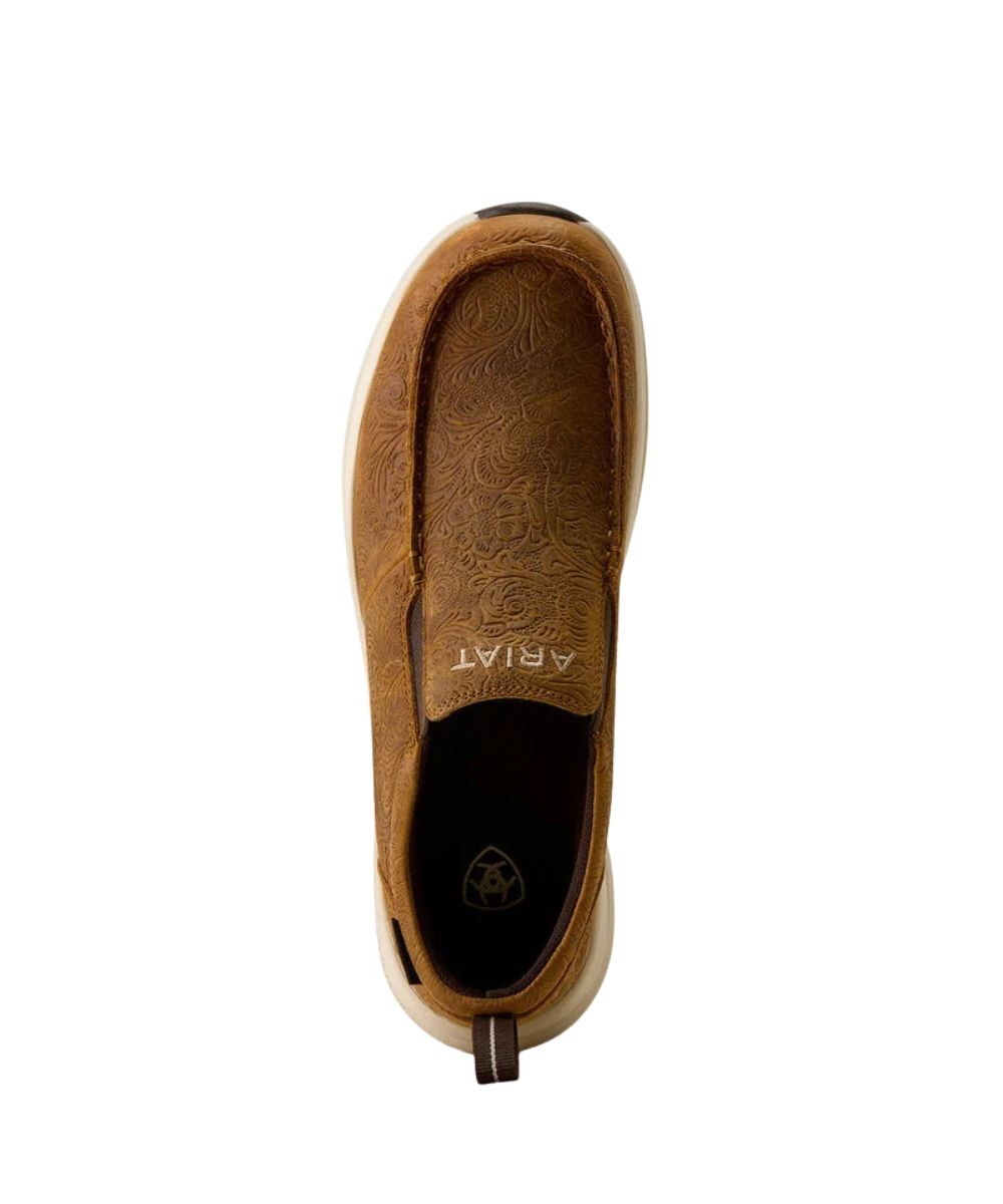 A top view of a brown slip-on shoe with embossed floral detailing, a thick cream midsole, and a brown outsole, shown against a plain white background.
