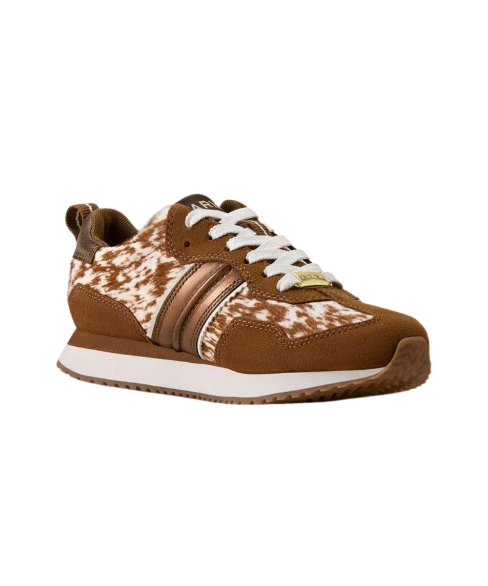 A low-top sneaker featuring a brown suede upper with a brown and white cow-print pattern on the side panels, metallic bronze side stripes, white laces, and a white midsole.