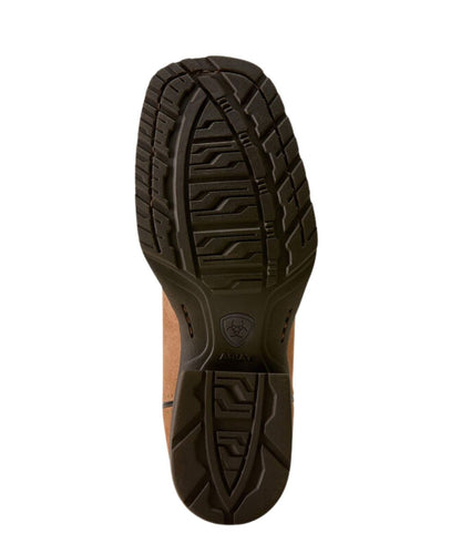 A top-down view of a brown boot's textured rubber outsole, showing deep tread patterns and the Ariat shield logo embossed in the center.
