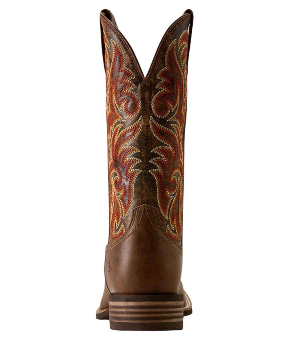 A single brown leather cowboy boot shown from the back, featuring intricate multicolor embroidered patterns in red, orange, yellow, and white on the shaft.