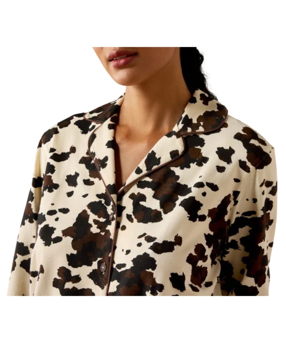 Close-up view of the cow print pajama set top featuring the brown piping along the collar and placket