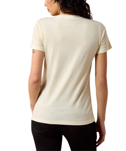 A woman shown from the back wearing a short-sleeve crewneck t-shirt in a warm off-white/cream color, paired with black pants, against a plain white background.