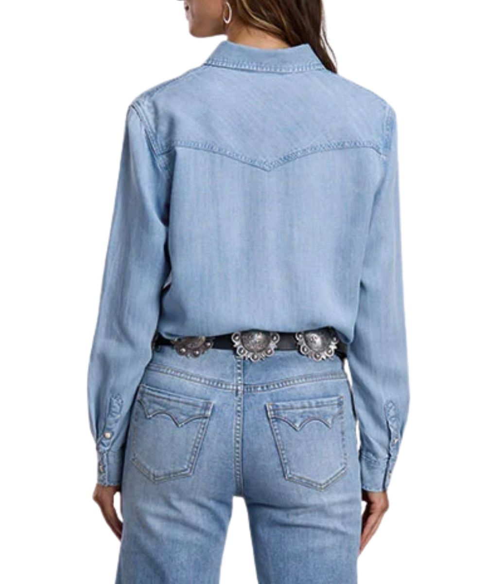 Back view of the women's blue light wash denim long sleeve snap shirt featuring the curved single point back yoke