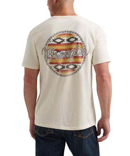 A man wearing a cream-colored Wrangler t-shirt, viewed from the back. The shirt features a large circular graphic on the back with a distressed Southwestern-style pattern in red, orange, yellow, and black, with the brand name 'Wrangler' written across the center in white script.