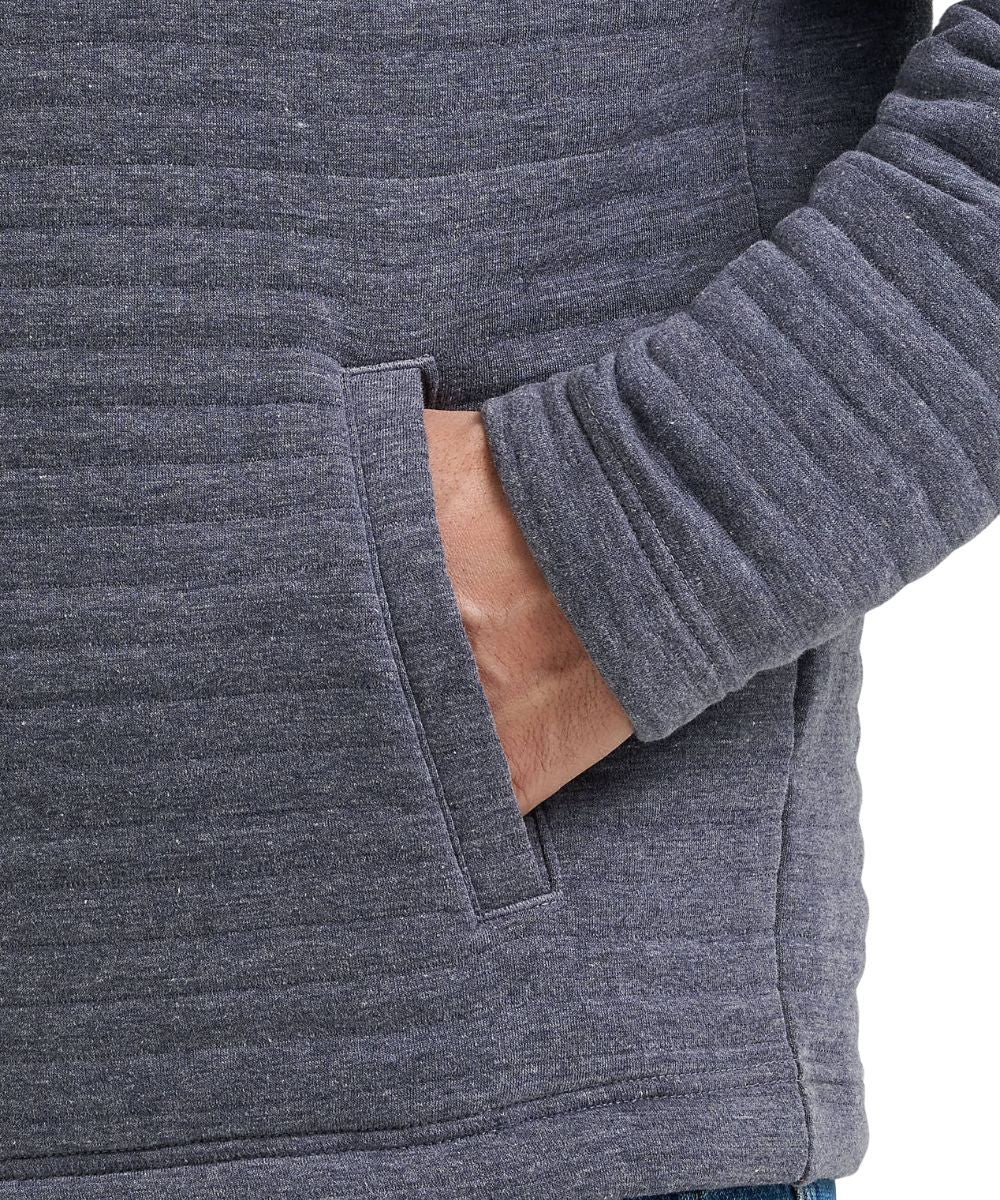 Close-up of a person wearing a dark heather gray ribbed knit hoodie with a side pocket, showing the sleeve cuff and hand in the pocket.