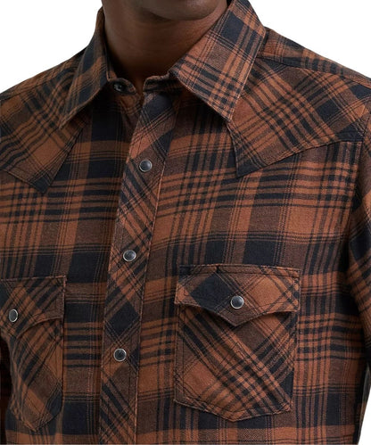 A close-up of a man wearing a brown and black plaid western-style button-down shirt, showing the collar, chest buttons, and a chest pocket.