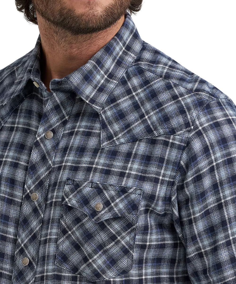 Close-up of a man wearing a blue and white plaid western-style button-down shirt, showing the collar, chest pocket, and snap buttons.