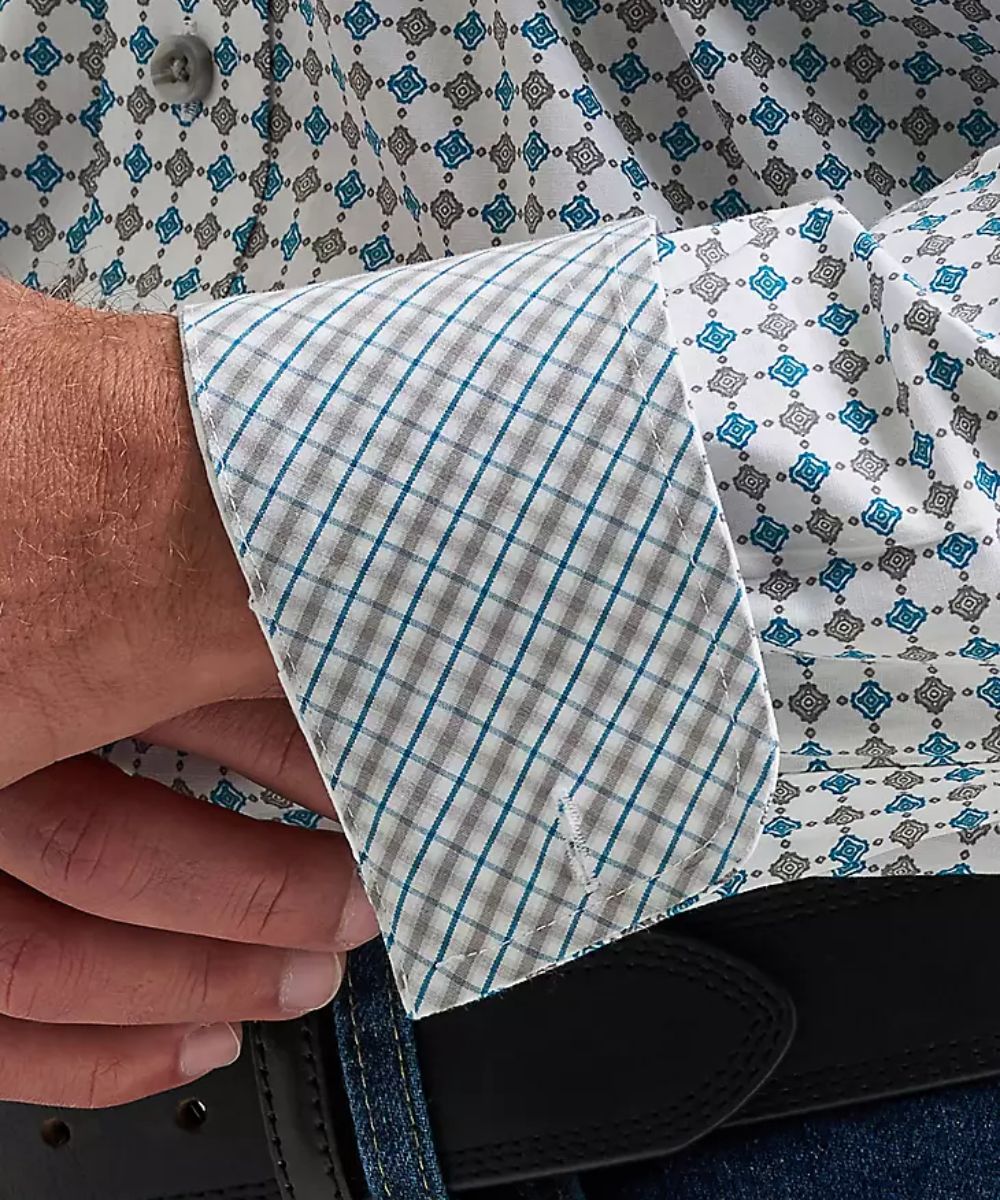 Close-up of a man wearing a long-sleeve button-down shirt with a white, blue, and gray geometric pattern.