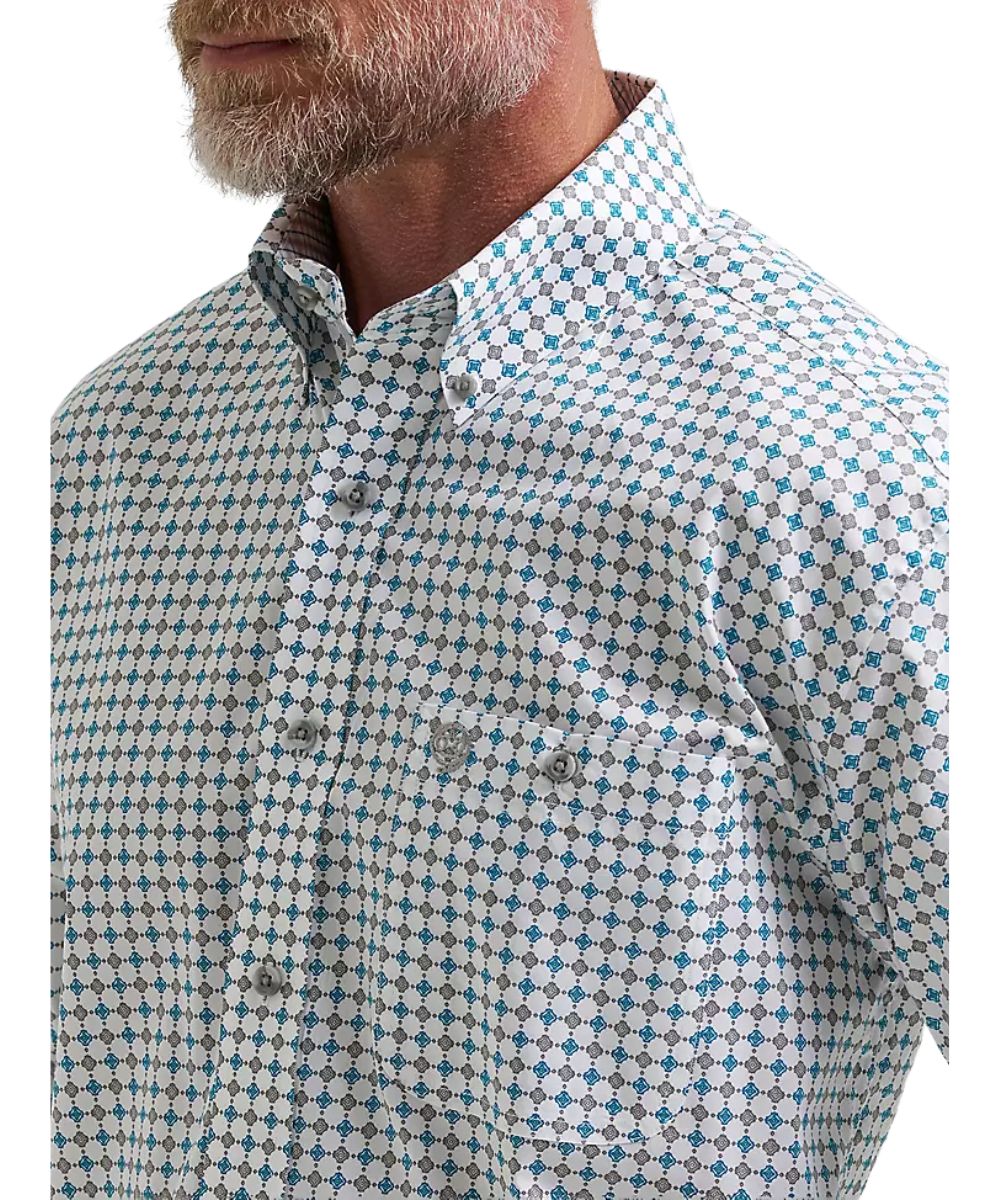 Close-up of a man wearing a long-sleeve button-down shirt with a white, blue, and gray geometric pattern.