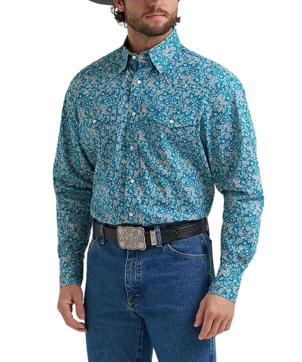 A man wearing a long-sleeve western-style button-down shirt with a blue and white floral pattern, paired with blue jeans and a black belt with a silver buckle.