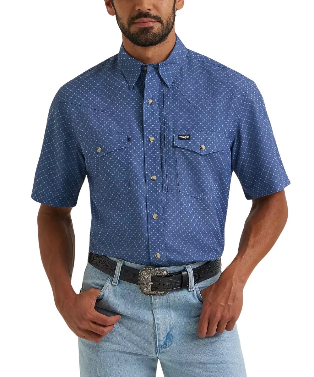 A man wearing a blue short-sleeve button-down shirt with a white micro-dot pattern, paired with light blue jeans and a black belt, shown from the chin down on a white background.