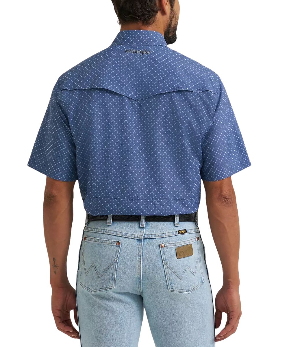 A man viewed from the back wearing a blue short-sleeve western shirt with a small white geometric pattern, paired with light blue jeans.