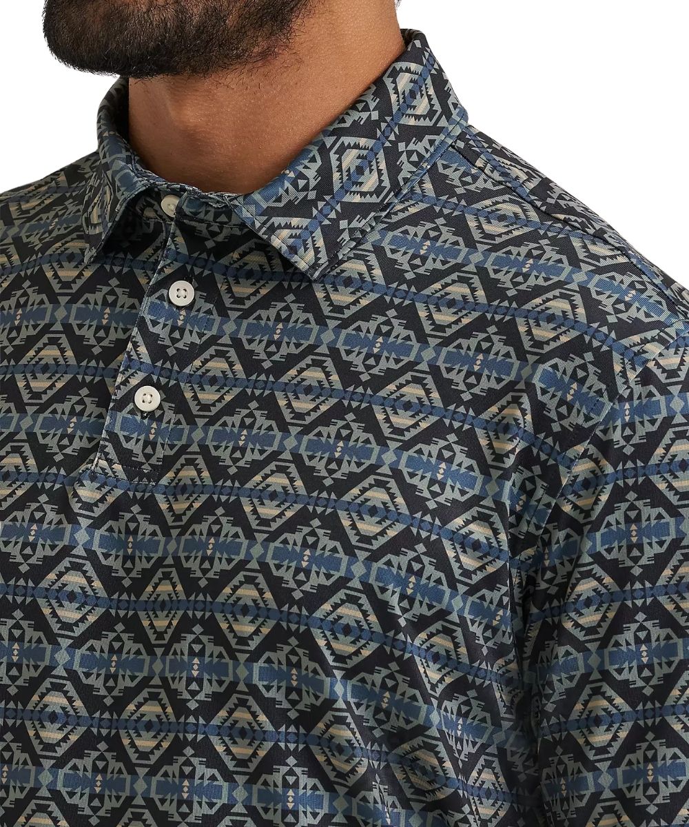 Close-up of a men's button-down shirt with a dark navy and blue geometric ikat pattern, featuring a collar and white buttons, worn by a model.