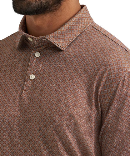 Close-up of a man wearing a collared short-sleeve polo shirt with a brown and orange geometric diamond pattern and white buttons.