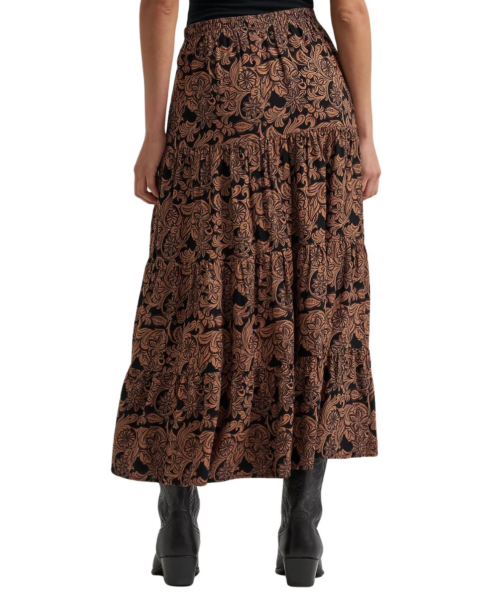 A model from the waist down wearing a brown and black paisley patterned tiered maxi skirt with black ankle boots, shot against a solid white background.