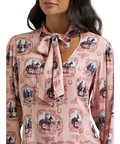 Close-up view of the women's pink blouse featuring the v-neckline with front tie, the button front closure, and puff sleeves