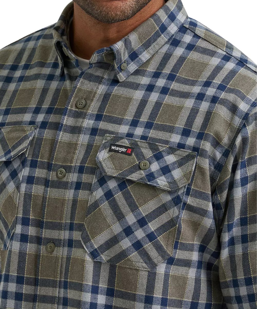 Close-up of a Wrangler men's plaid button-down shirt in a muted blue, gray, and beige pattern, featuring a chest pocket with a flap and a visible Wrangler logo tab.