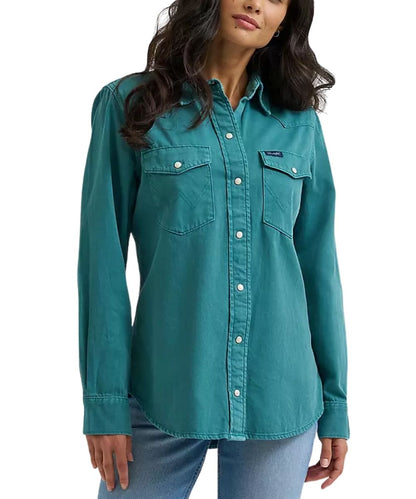 A woman wearing a teal long-sleeve western-style button-up shirt with two chest pockets and light blue jeans, shown against a plain white background.