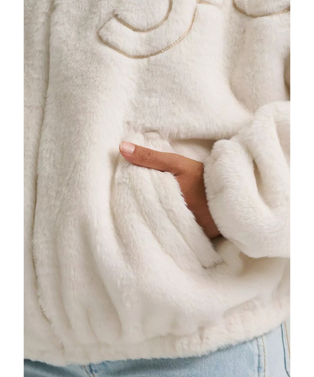 Close-up view of the angled hand pockets and polyester sherpa faux fur