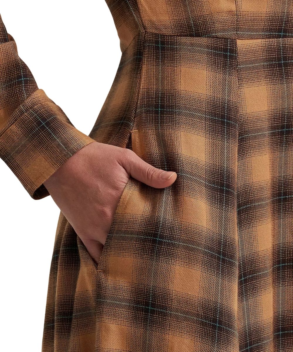 Close-up of a person wearing a brown and tan plaid coat with a pocket, showing the hand in the pocket against a white background.