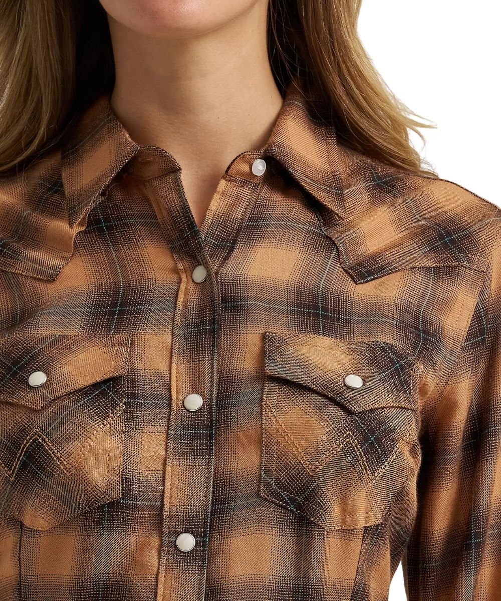 Close-up of a woman wearing a brown and tan plaid western-style button-up shirt with white snap buttons and chest pockets.