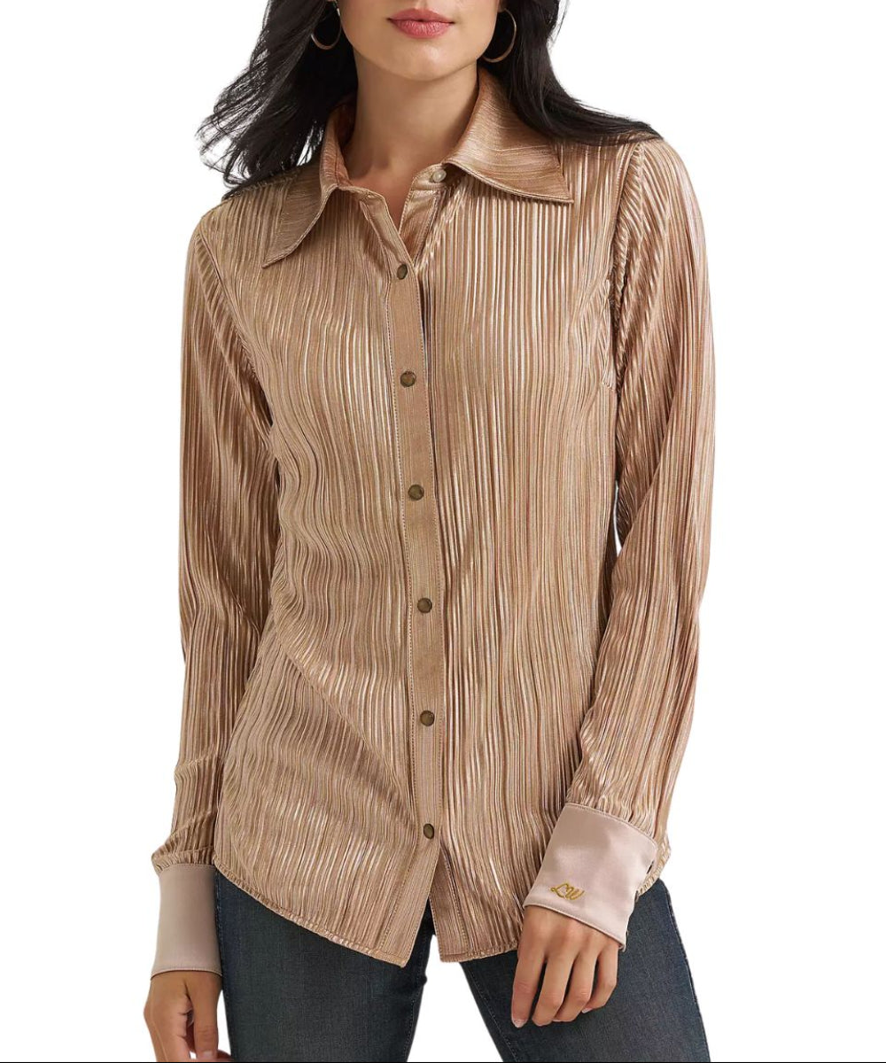 A woman wearing a long-sleeve button-up shirt with a vertical pleated texture in a metallic champagne beige color, paired with dark jeans against a plain white background.
